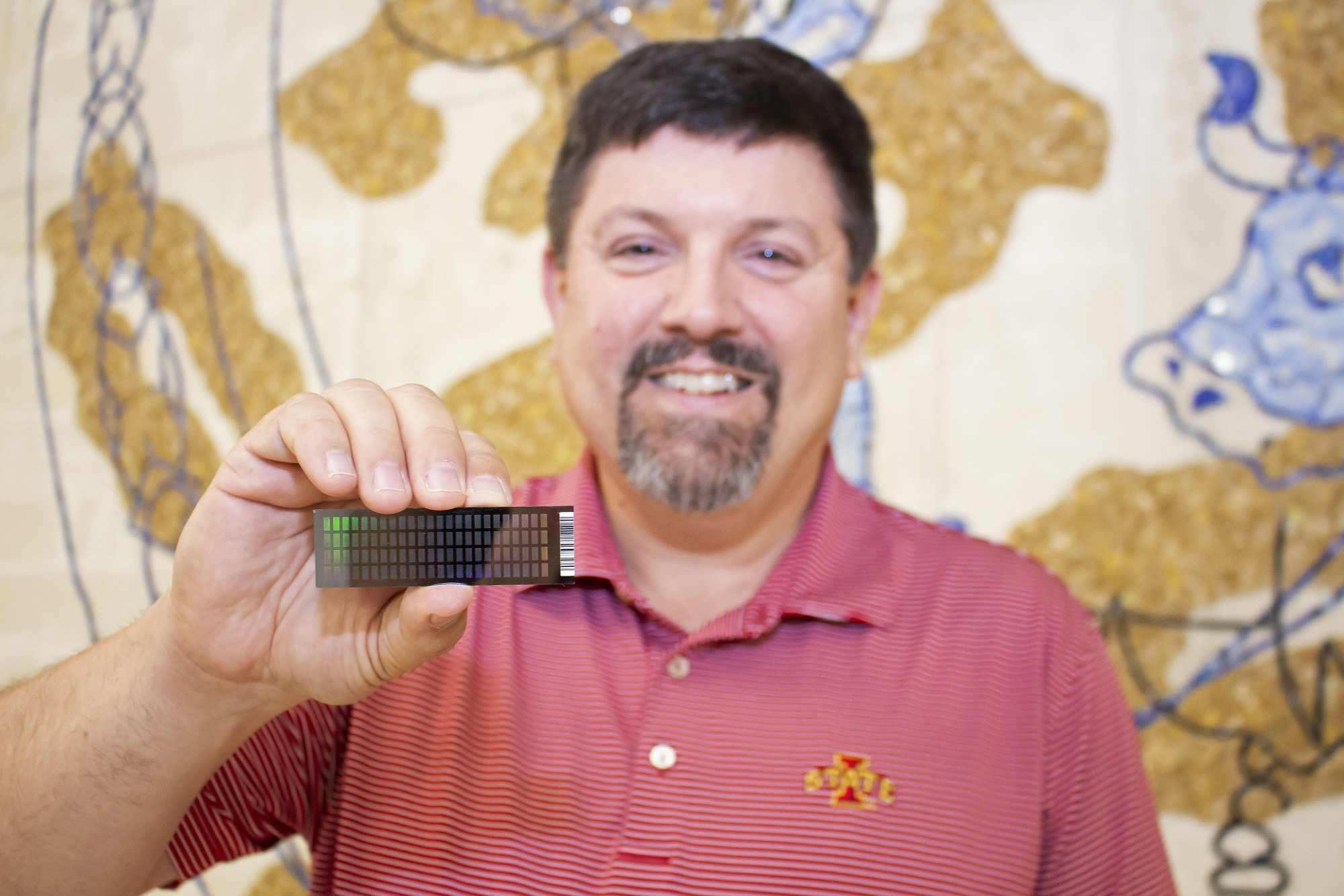 Smiling dark-haired man in red suit holding computer chip, background image