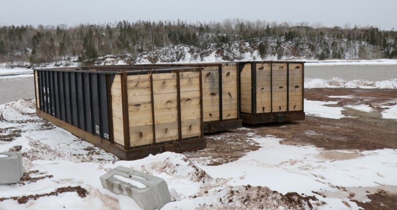 Three rectangular boxes sit on a snowy shore.